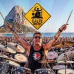 Een drummer met tal van mensen rond zich met de Ifach rots in de achtergrond